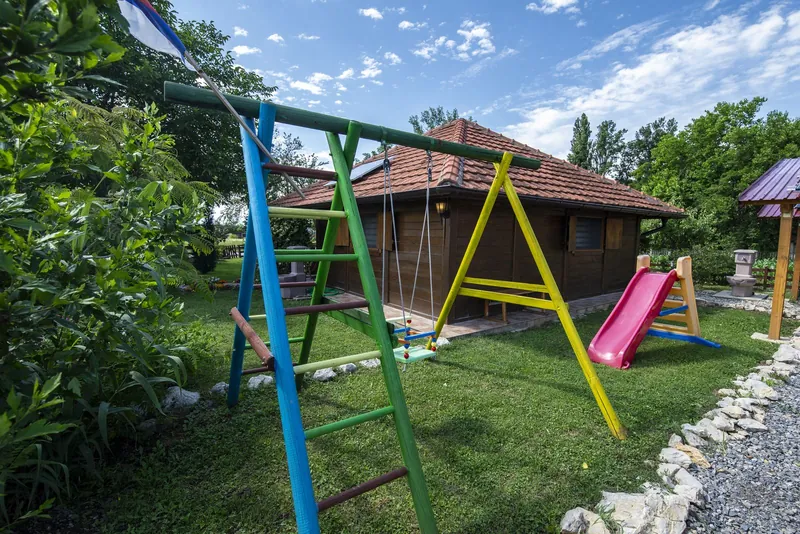 Restaurace s dětským hřištěm: dřevěné houpačky a skluzavka na zahradě u hospůdky