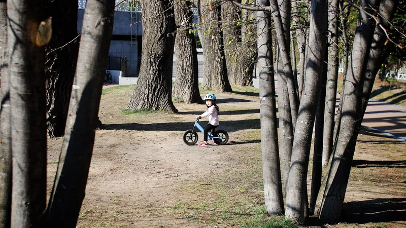 Cyklovýlety s dětmi: malá holčička s helmou na odrážedle v jarním parku