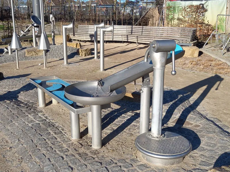 Wasserspielplatz mit Handpumpe und Wasserrinne, bereit für den Saisonstart im Frühsommer