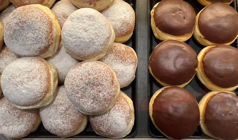 Krapfen mit Puderzucker und Schokoladenglasur in der Auslage einer Konditorei