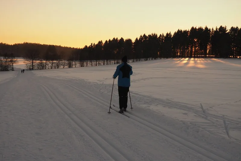 Langläufer in der Loipe bei Sonnenuntergang, Wintersport mit Kindern ausprobieren