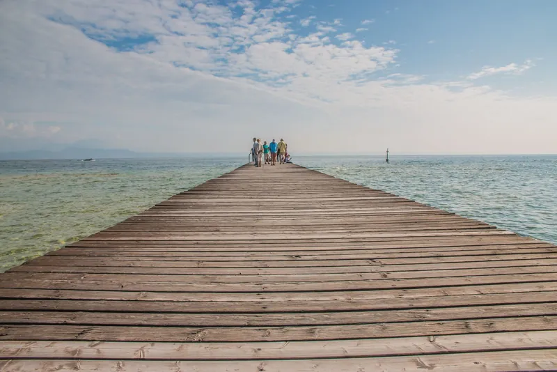 Wooden pier over clear water in Sirmione on Lake Garda, a calm spot for shoulder season travel with kids