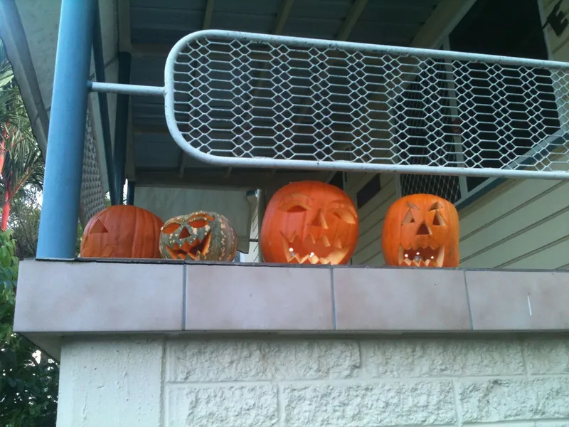 Row of carved jack-o-lantern pumpkins on a wall, a classic sight of Halloween with kids
