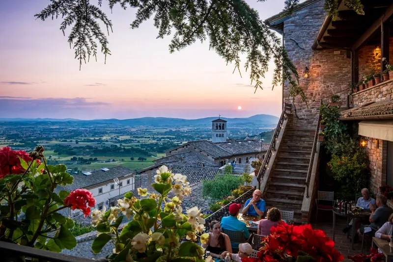 Family dinner on a terrace in Assisi at sunset, a typical scene of eating out with kids in Italy