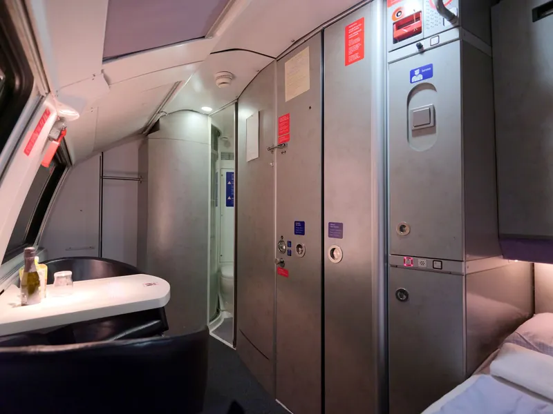 Sleeper compartment with bed, table and private shower on a Nightjet, cosy for a night train with kids