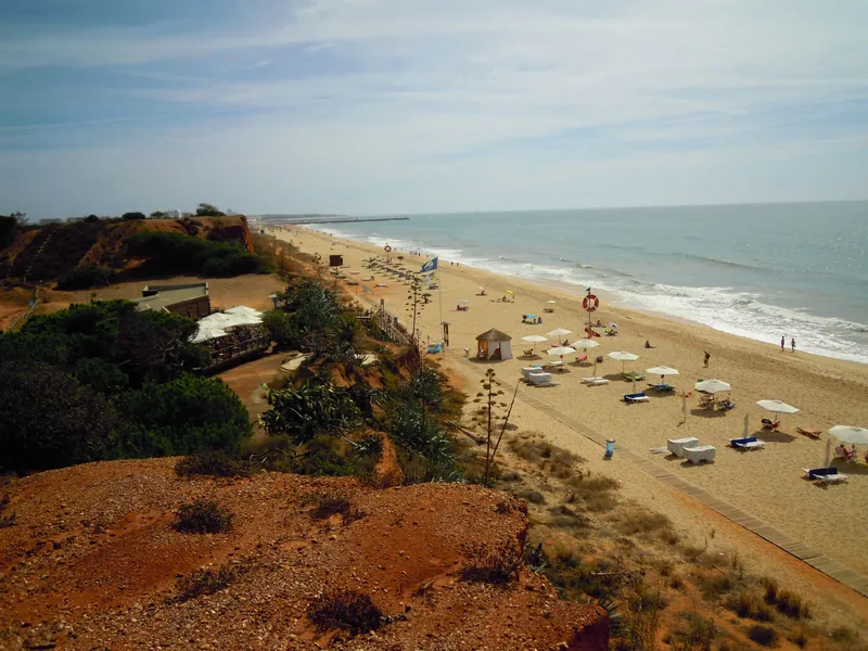 Quiet sandy beach on the Algarve coast with a few parasols, ideal for September travel with pre-schoolers